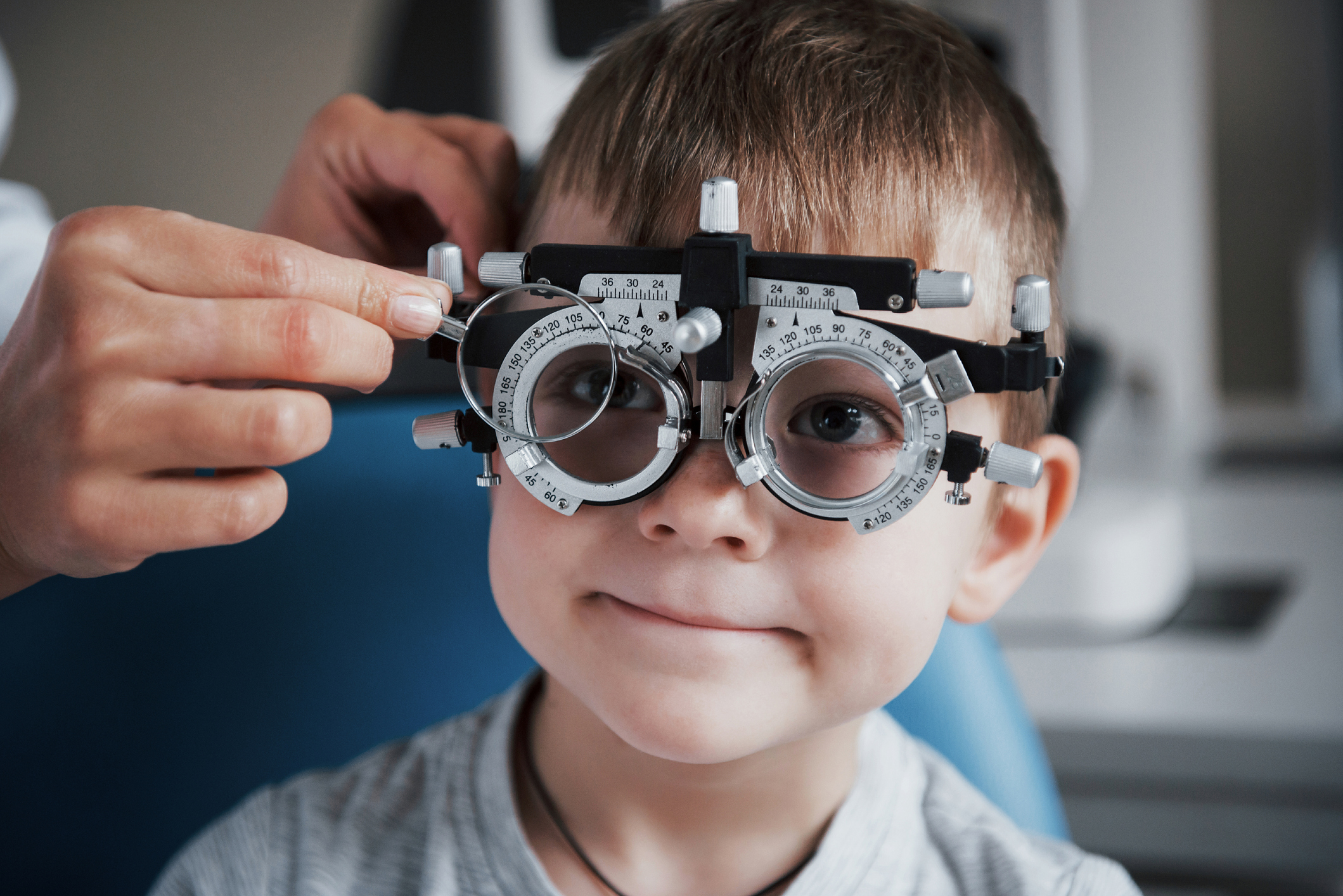 Tuning the intrument. Little boy with phoropter having testing his eyes in the doctor's office for back to school health checklist