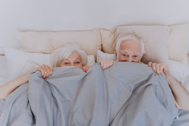 Beautiful senior couple enjoying time together at home - Romantic moments at home, elderly couple in bed needs to rekindle their sex life