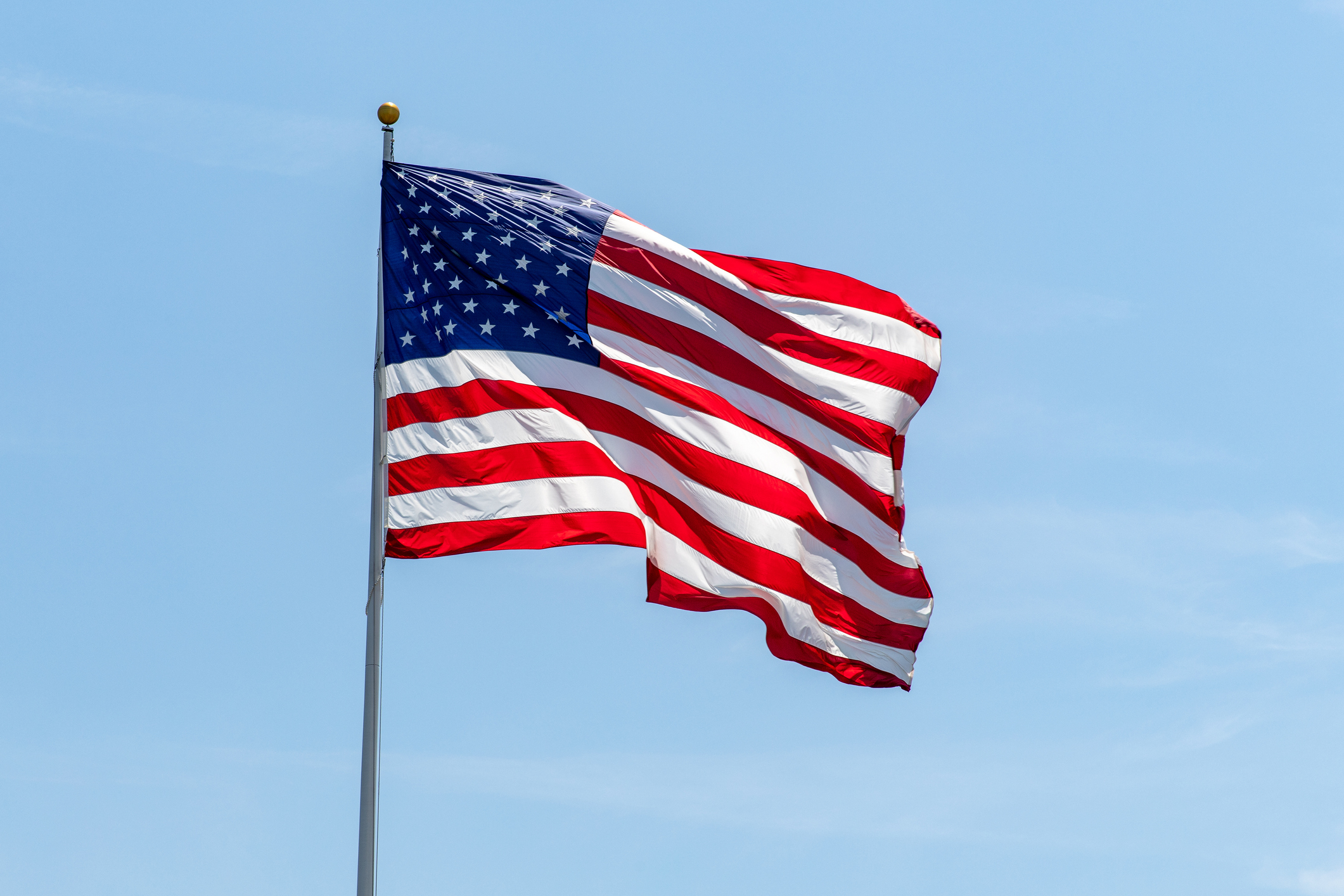 American flag waving on pole with bright vibrant red white and blue colors, negative space in the Hamptons