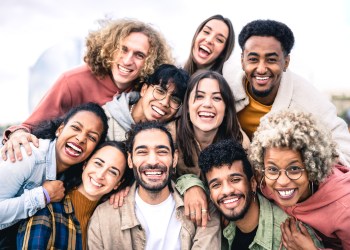 Multi ethnic guys and girls taking selfie outdoors with backlight - Happy life style friendship concept on young multicultural people having fun day together in Barcelona - Bright vivid filter