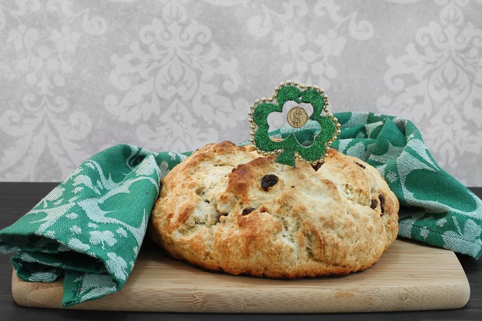 A full loaf of fresh baked Irish soda bread surrounded by a green shamrock towel. Close up with copy space.