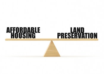 Land Preservation and Affordable Housing - two town taxes - on a Wooden Seesaw Scale Sitting Balancing
