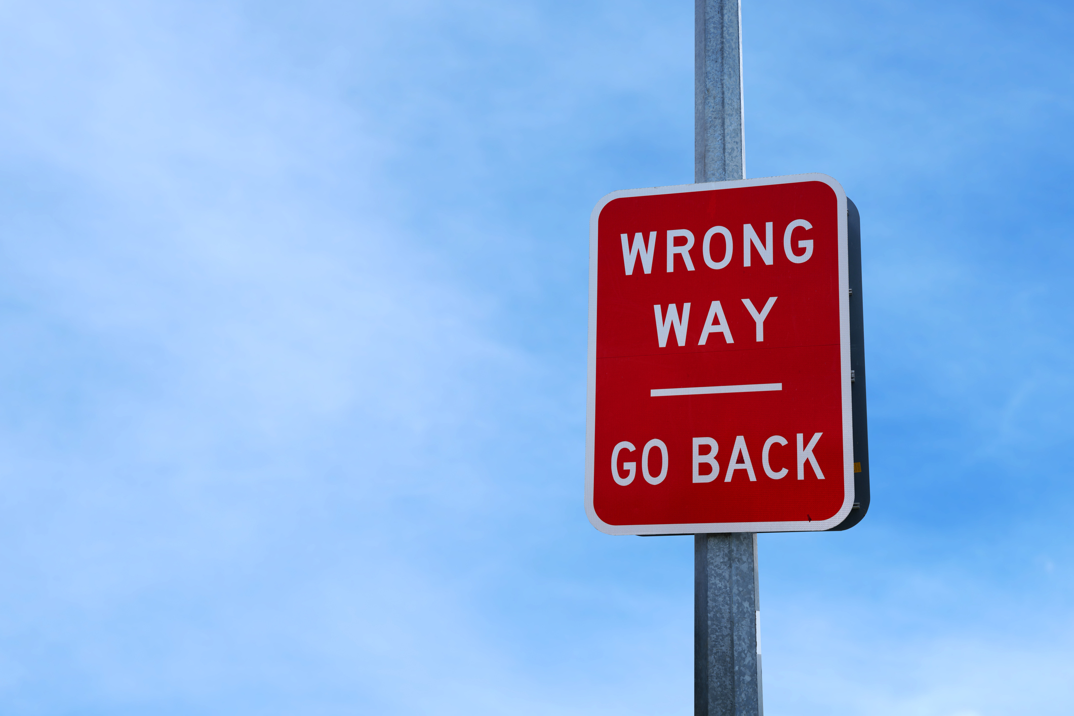 Red wrong way go back sign against a blue sky - learn lessons from your mistakes
