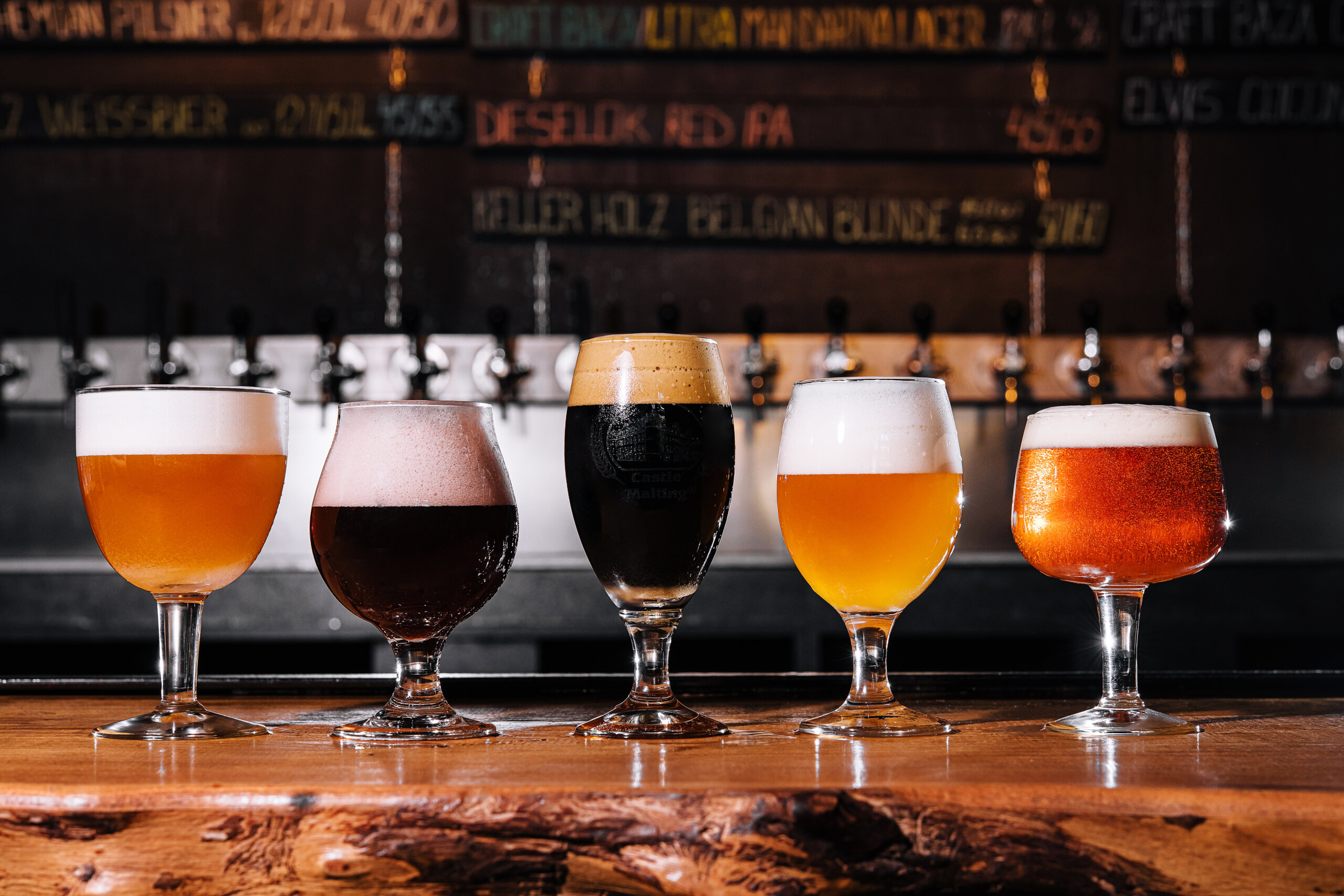 different types of craft beer in glasses on table in breweries pub interior in daylight