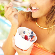 Portrait of a happy young mixed race woman enjoying frozen yogurt with blueberry and strawberry fruit toppings outside. ice cream hamptons north fork