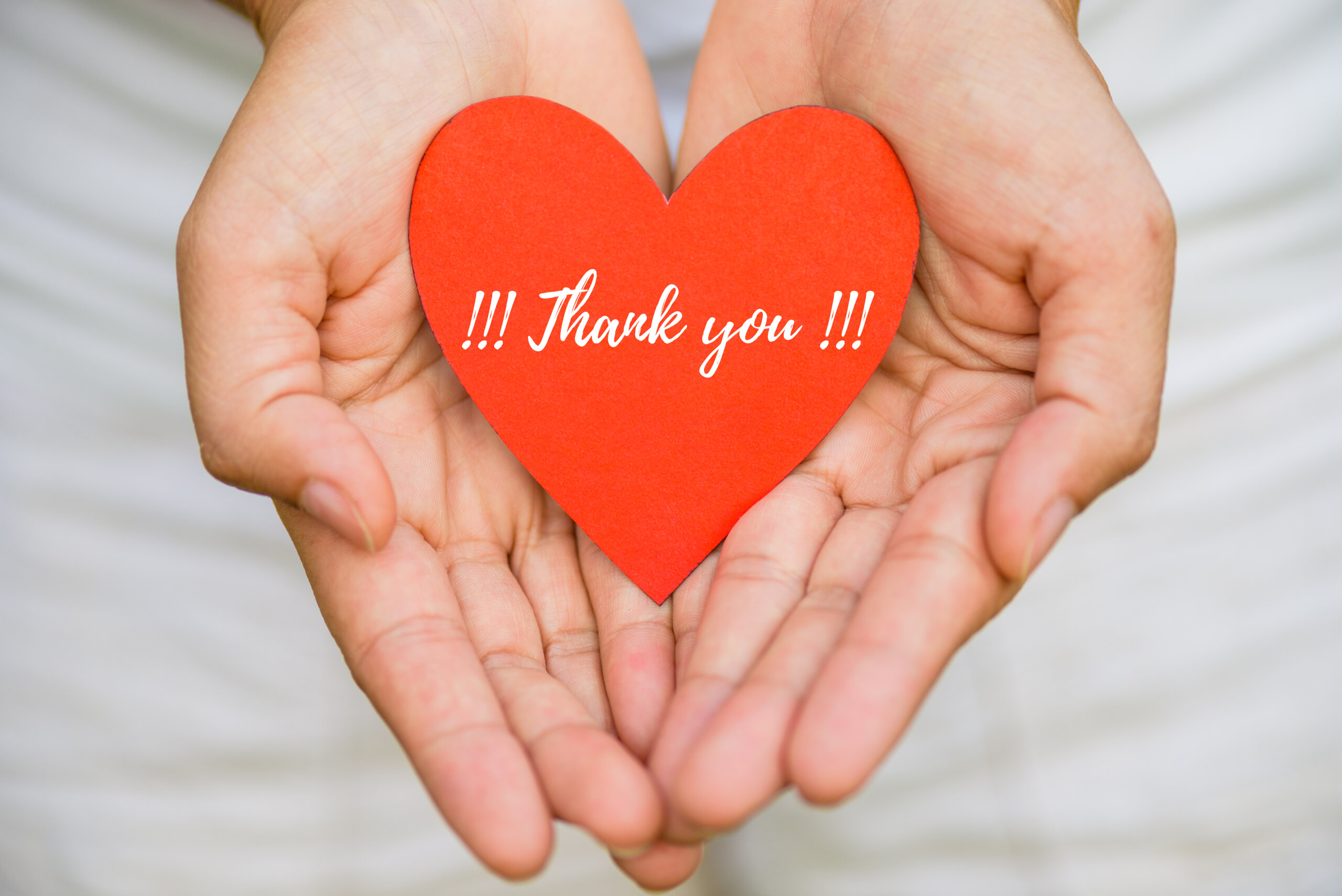 Young woman hand holding red heart paper with THANK YOU message. Thankful concept.