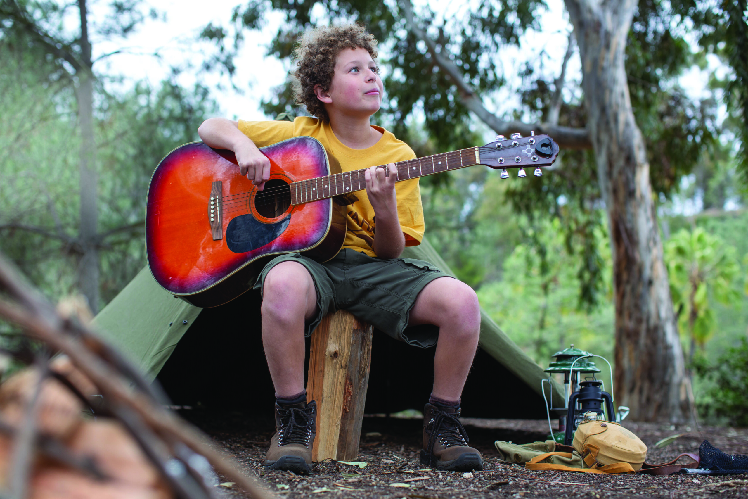 Boy playing guitar at a Jewish summer camp campsite