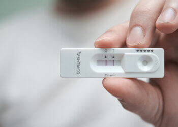 Close-up of a hand holding a positive antigen test for COVID-19. SARS-CoV-2 antigen rapid test kit.