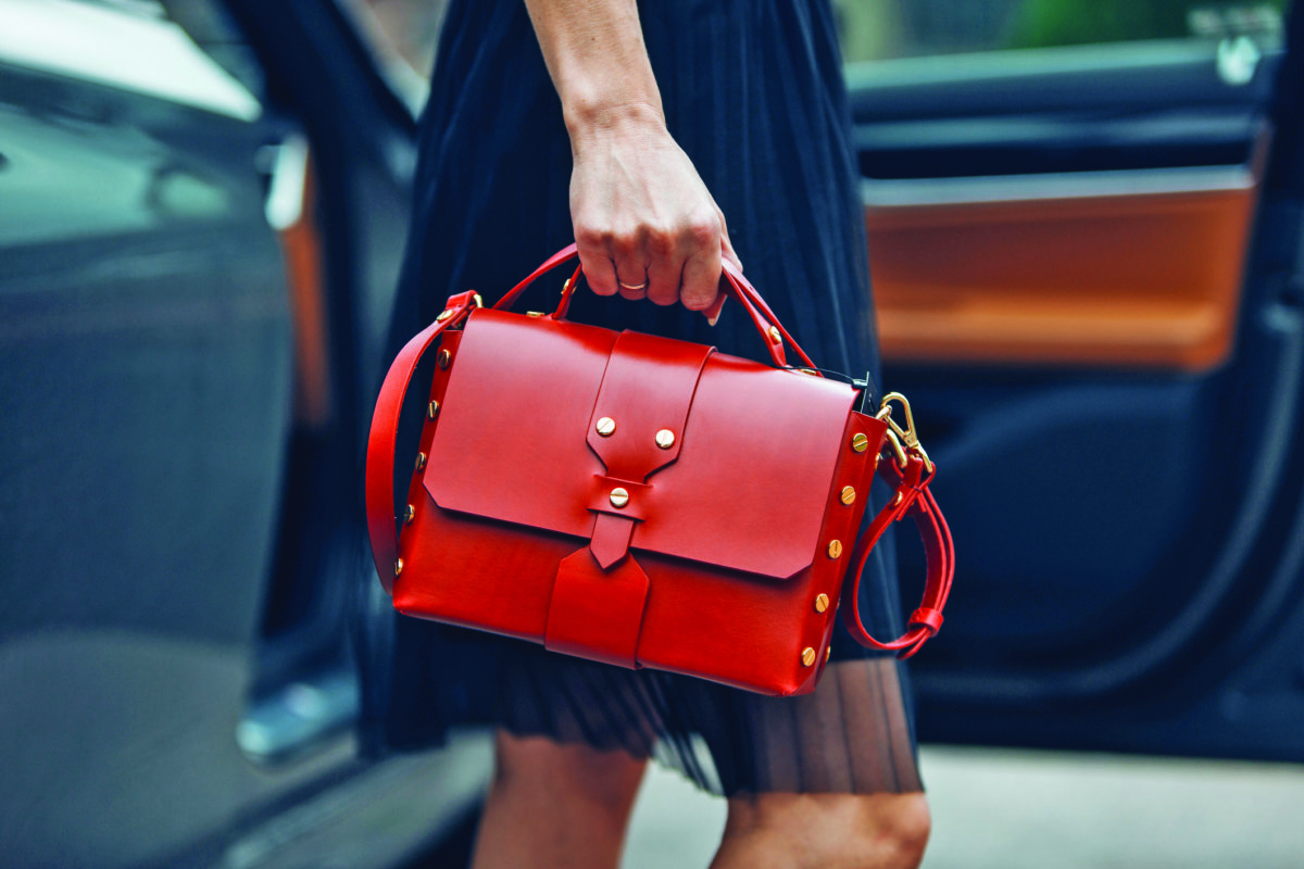 Women is holding a Balenciaga handbag near luxury car