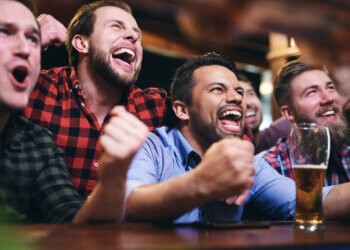 Men watching television and cheering for team at football bar for game day specials