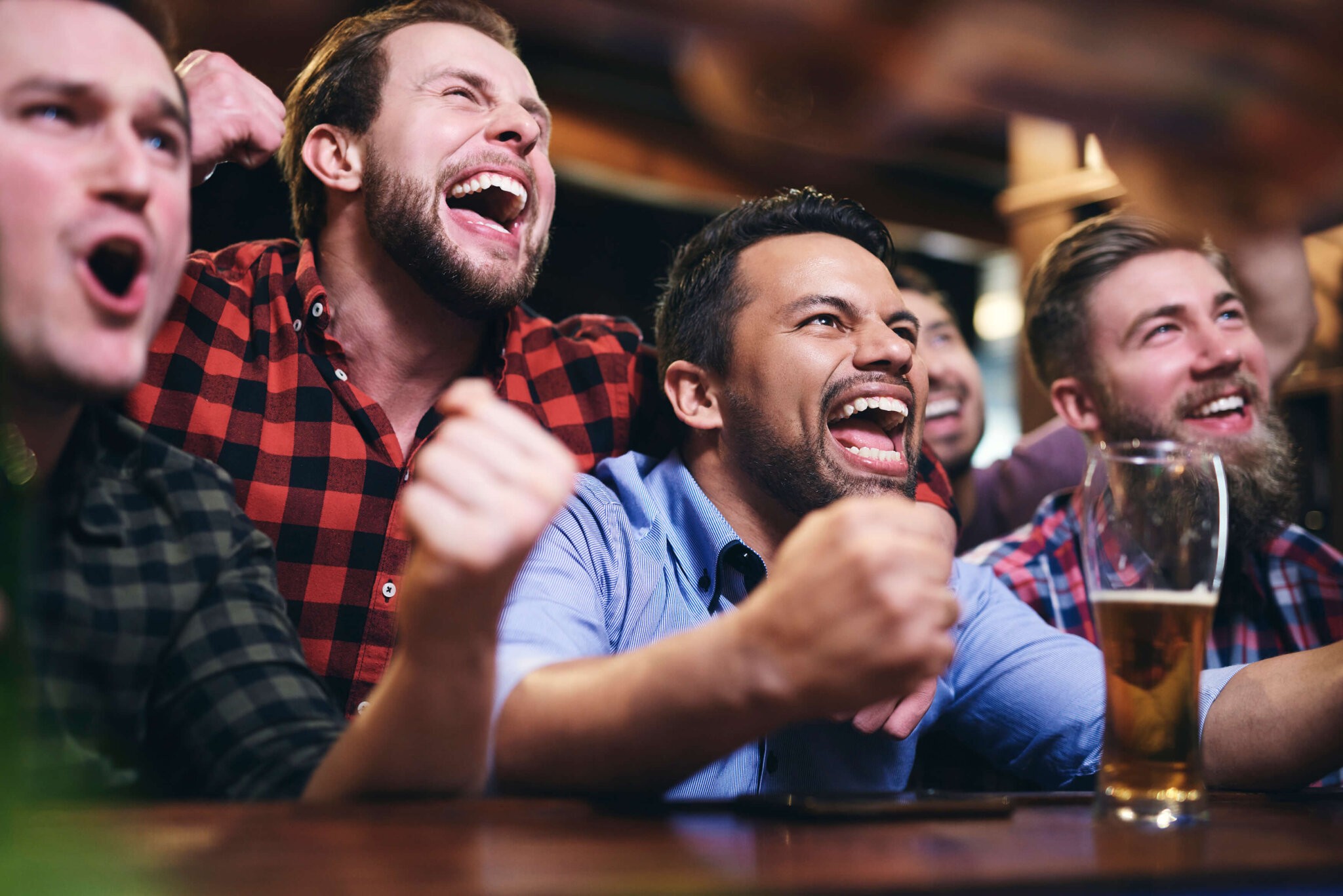 Men watching television and cheering for team at football bar for game day specials in the Hamptons