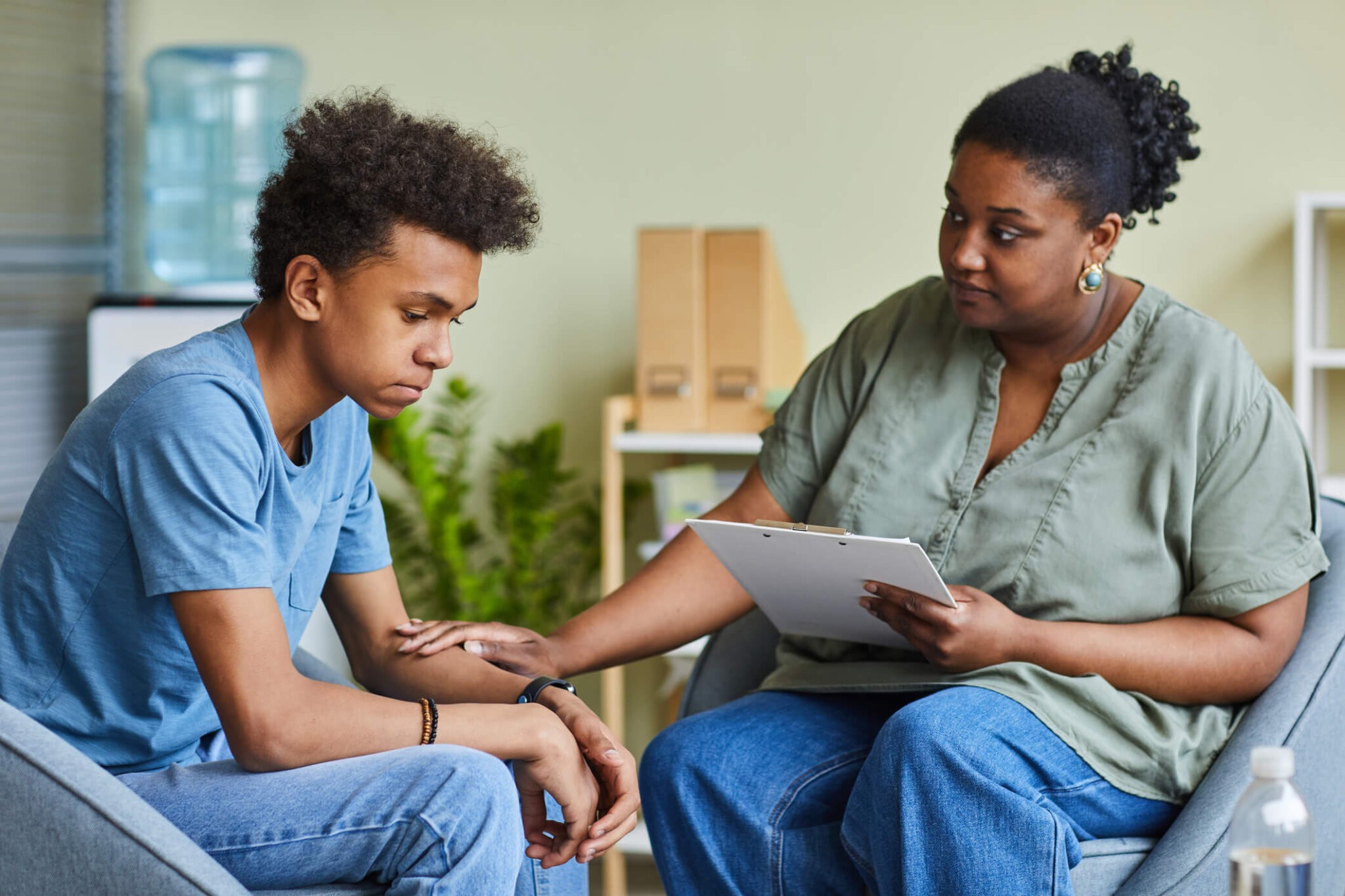 African psychologist supporting depressed teenage boy feeling guilty about behavior during therapy at office Mental Health