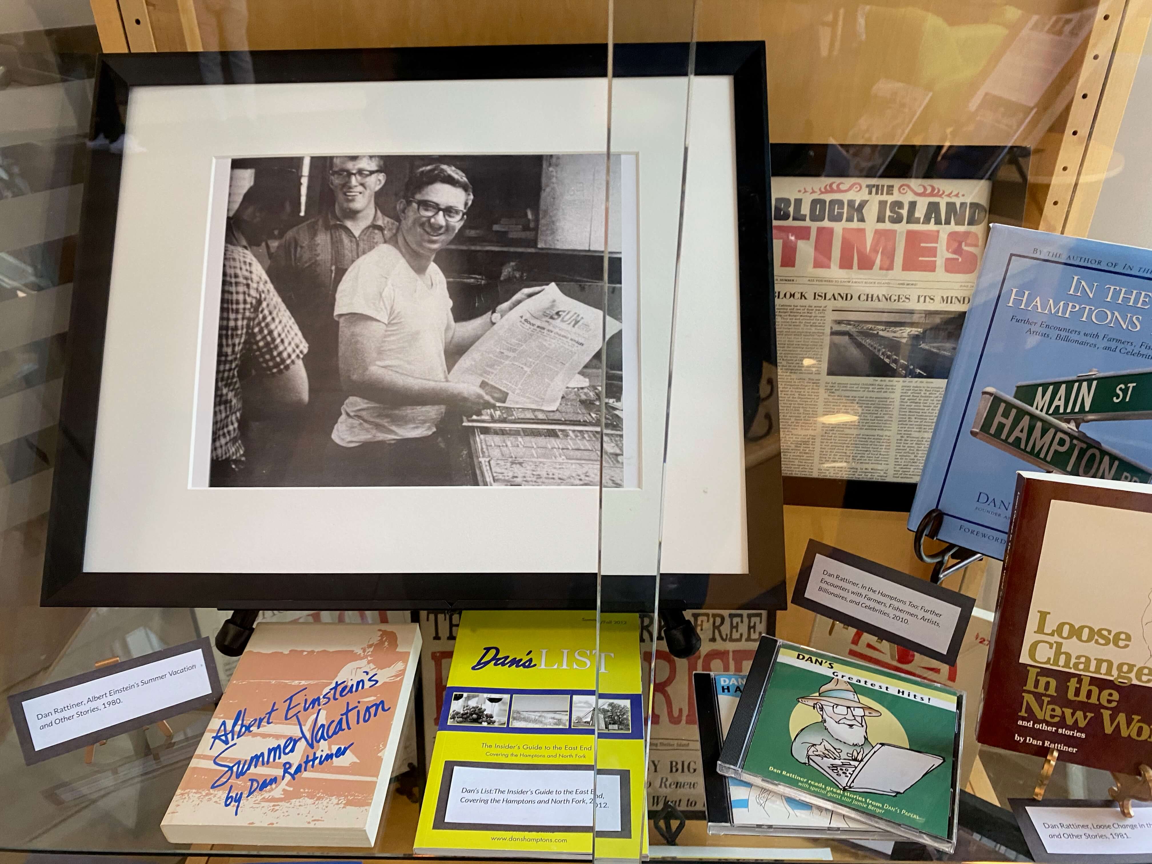 A photo of a young Dan Rattiner and copies of his published books and other Dan's Papers related media on display at Stony Brook Southampton Library