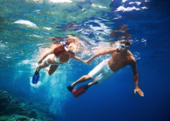 A young couple enjoying snorkeling in the turquiose water of the sea Palm Beach