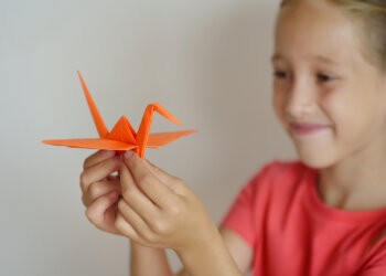 The girl puts origami from paper. Lesson of origami for kids