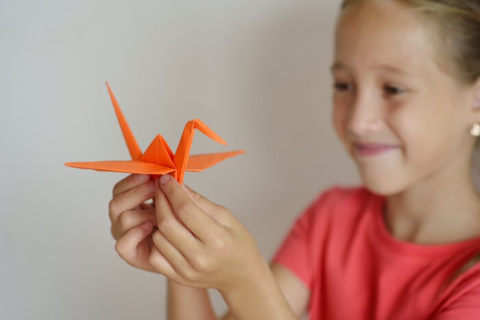 The girl puts origami from paper. Lesson of origami for kids