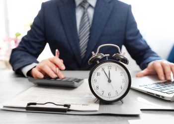 Business man using calculator. Annual tax settlement. Tax income concept with clock five minutes to midnight