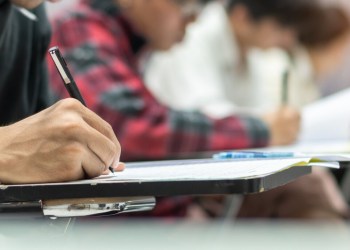 Exam at school with student’s taking educational admission test in class, thinking hard, writing answer in university classroom, education and world literacy day concept