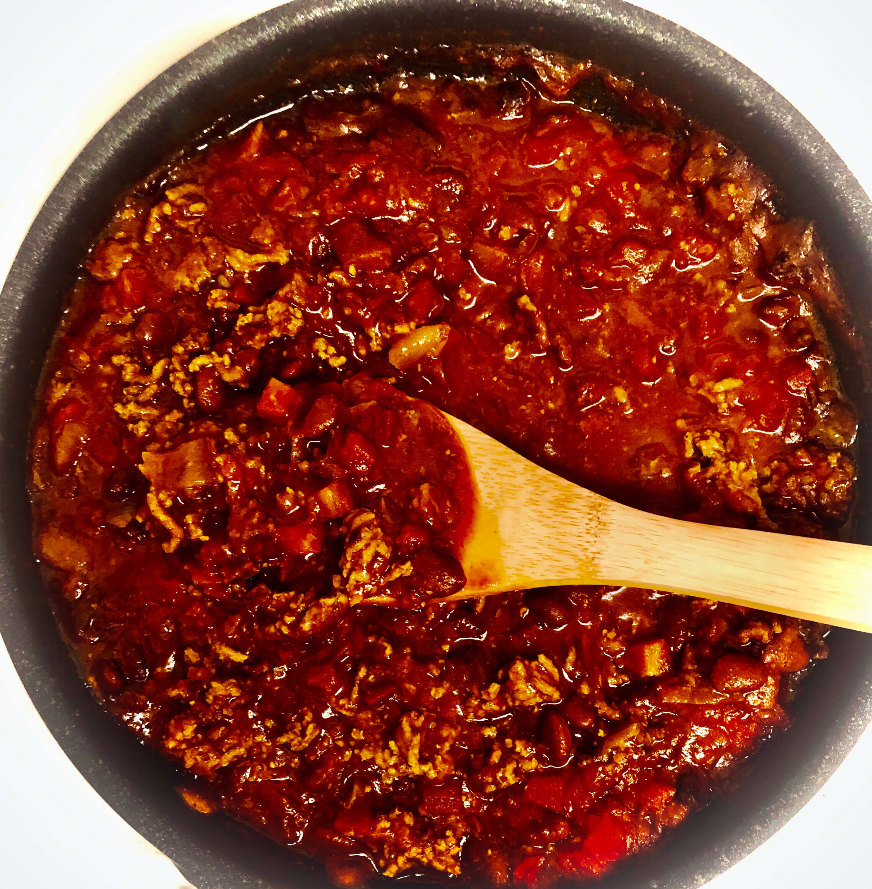 A batch of homemade Chili Con Carne cooked in a skillet with a wooden spoon on a cold winter day in a Hoboken, New Jersey apartment.