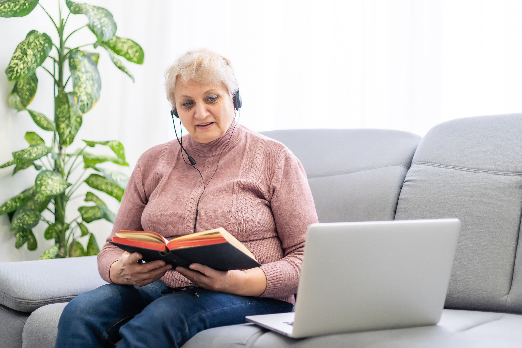 Woman with bible and laptop in front of her connected to online church services durring the covid 19 outbreak