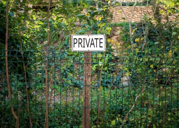 View Of Signboard On Fence Against Plants
