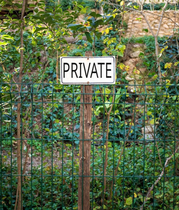 View Of Signboard On Fence Against Plants