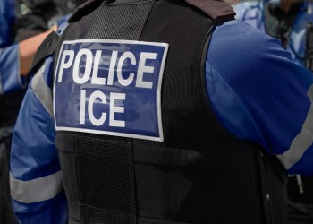 Ice Police agents – Immigration and Customs Enforcement. Close-up of POLICE ICE marking on the back of worn by a trio of DHS police officers at the scene of an incident.