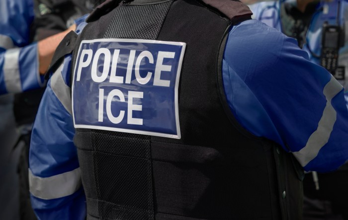 Ice Police agents – Immigration and Customs Enforcement. Close-up of POLICE ICE marking on the back of worn by a trio of DHS police officers at the scene of an incident.