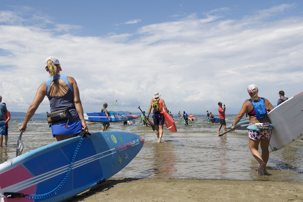 Standup paddlers enter the water - like in Stand Up for the Ocean