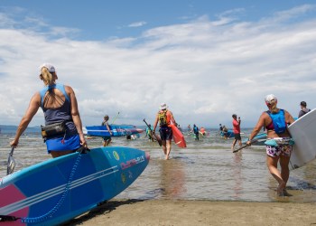 Standup paddlers enter the water - like in Stand Up for the Ocean